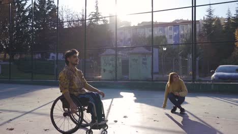 Behinderter-Mann-Spielt-Basketball-Im-Rollstuhl-Mit-Freundin-Im-Freien.